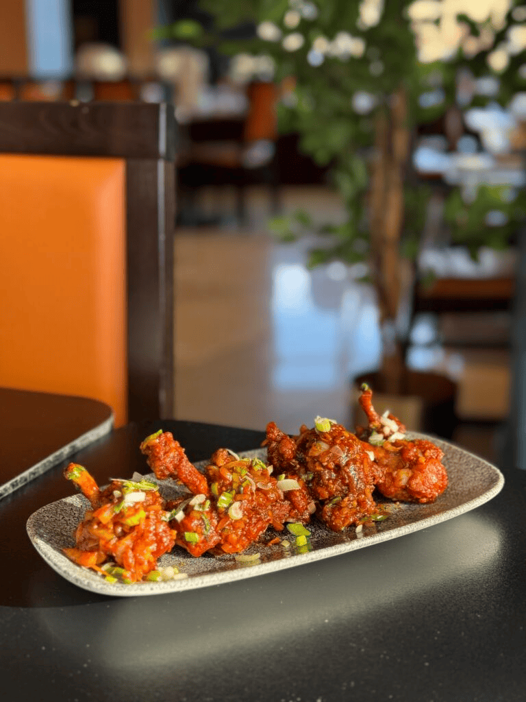 Crispy glazed chicken lollipops appetizer garnished with spring onions at Cinnamon Lounge