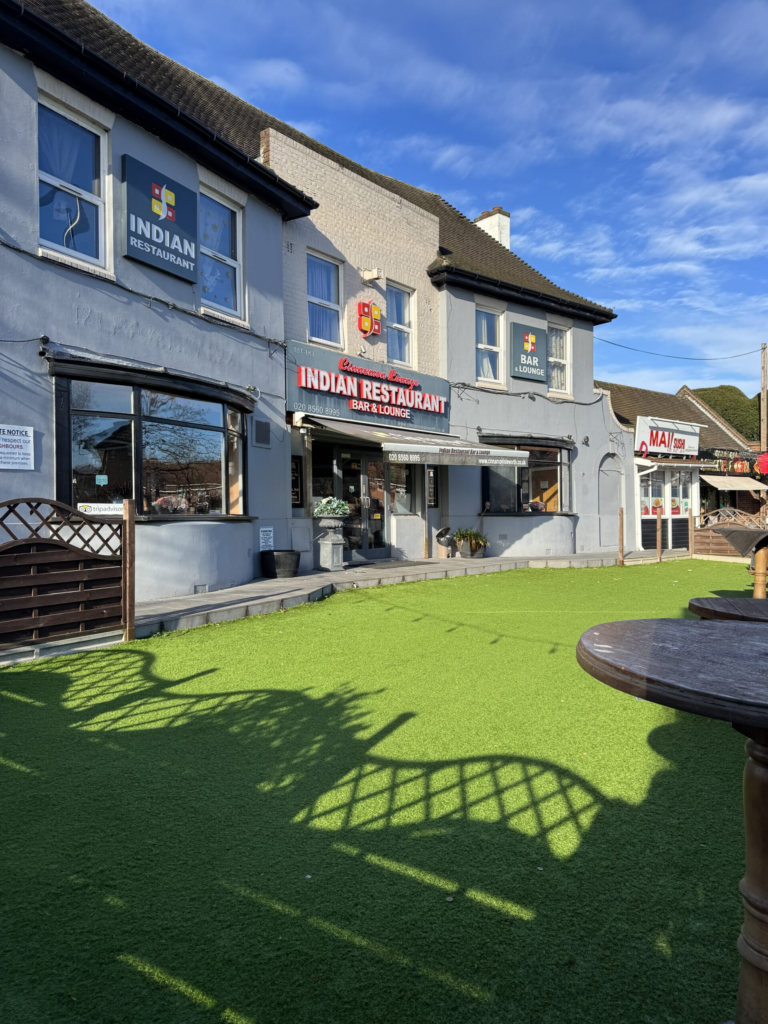 Exterior facade and artificial turf patio seating at Cinnamon Lounge Indian Restaurant Bar & Lounge in Isleworth.