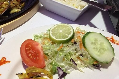Fresh-garden-side-salad-garnished-with-sliced-lime_-cucumber_-and-tomato-served-at-Cinnamon-Lounge.