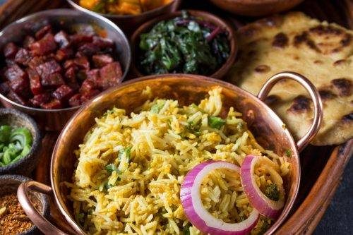 Traditional Pakistani biryani served in a copper handi bowl with naan bread and side dishes.